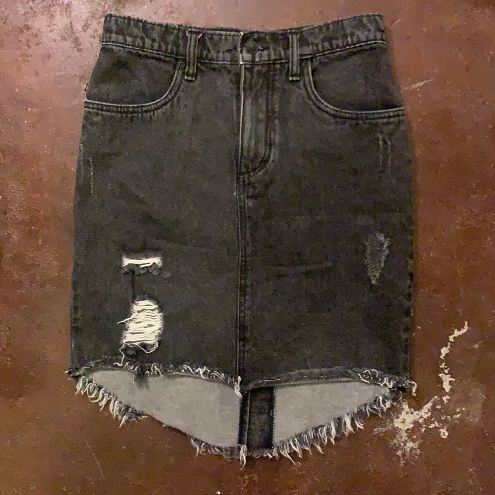 Rusty black denim distressed mini skirt. Longer in back with a button kick pleat